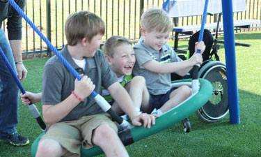 L to R: Brothers Conner, Cayden and Cooper Long enjoy one of the accessible swings at Roll Around the Park.
