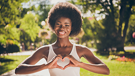 Woman in a park creates a heart symbol with her hands