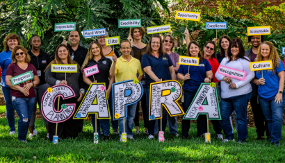 people pose in front of CAPRA letter sign