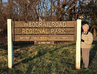 Joan Rokus stands next to the W&OD Railroad Regional Park sign.