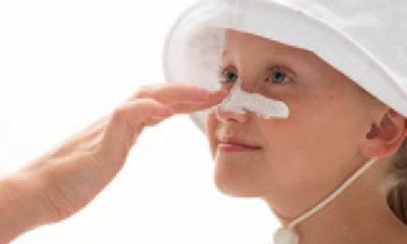 Child applying sunscreen to nose